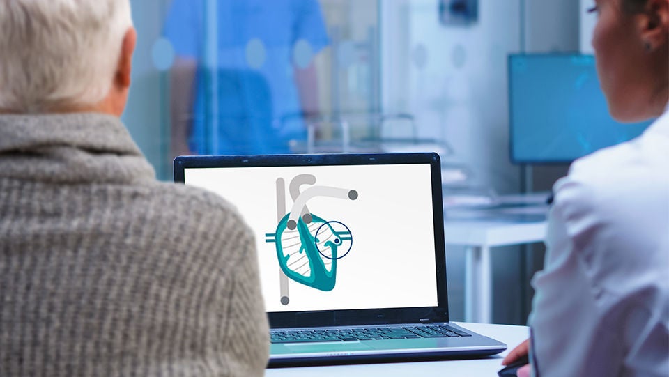 Healthcare provider showing patient diagram of heart on computer screen.