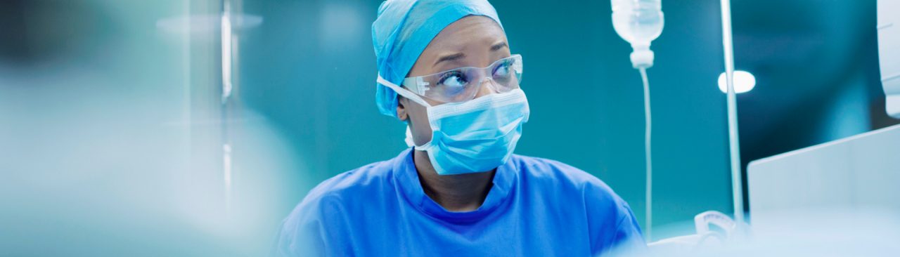 An image of a doctor in the operating room wearing a medical mask and glasses.