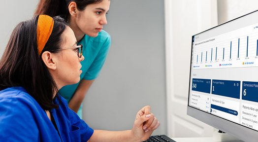 Two healthcare professionals looking at a computer screen showing charts and data.