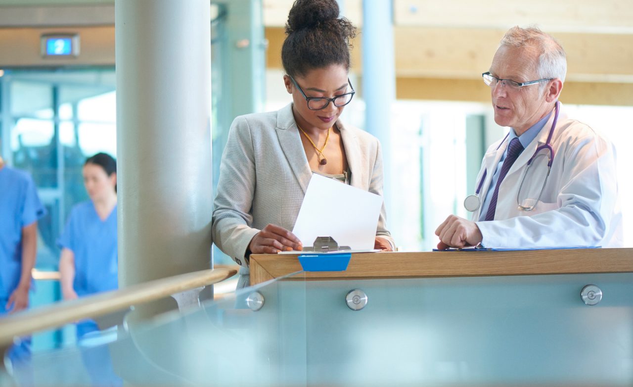 A doctor and an administrator discussing documents in a hospital.