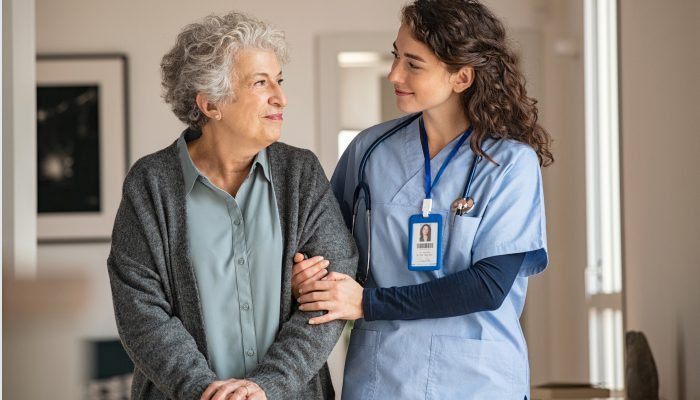 A healthcare professional walking and talking with a patient while supporting their arm.