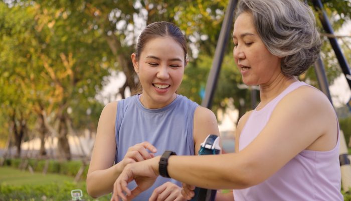 Two women on a walk outdoors checking one of their fitness watches.