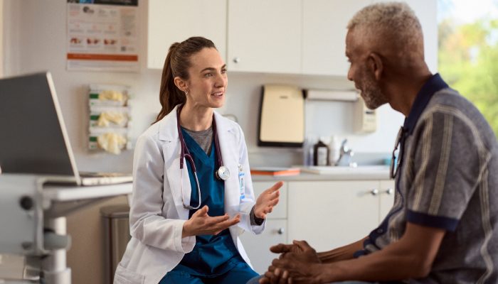 A patient and doctor in an exam room having a conversation.