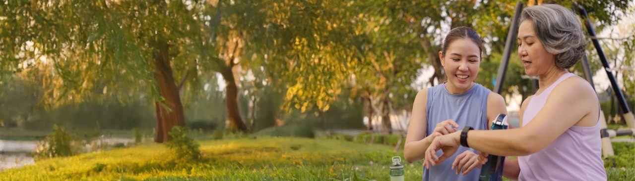 Two women on a walk outdoors checking one of their fitness watches.