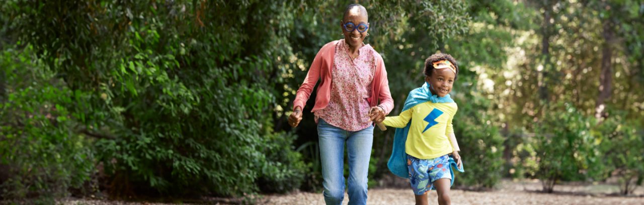 A smiling woman running after her grandchild outdoors.