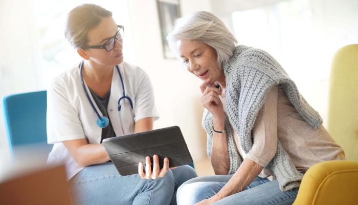 A doctor showing a tablet device to a patient in a sitting area.