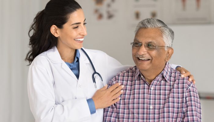 A smiling doctor with a smiling patient in an exam room.