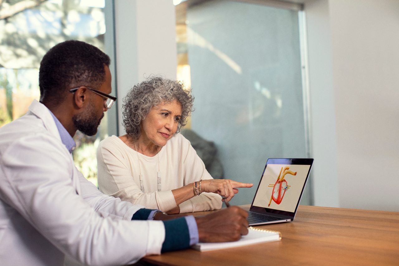 A healthcare professional showing medical images to a patient in an exam room.