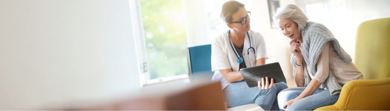 A doctor showing a tablet device to a patient in a sitting area.